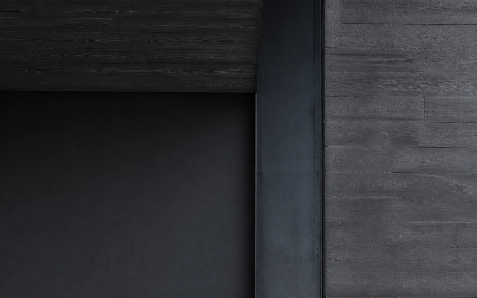 The junction where board-marked concrete meets a blackened steel column and a dark oak soffit
