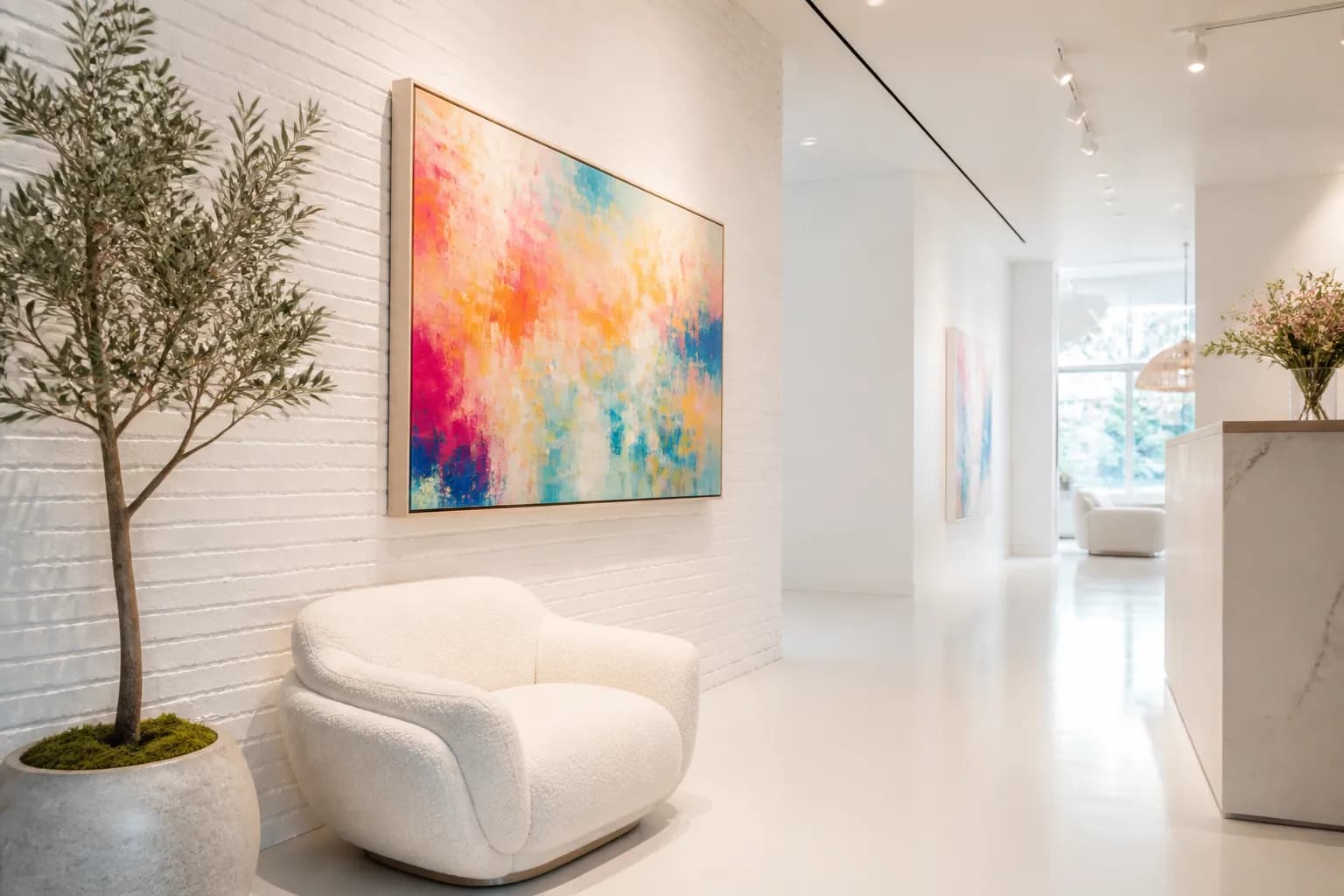 A white brick hallway in the studio with one large abstract painting and a cream lounge chair.