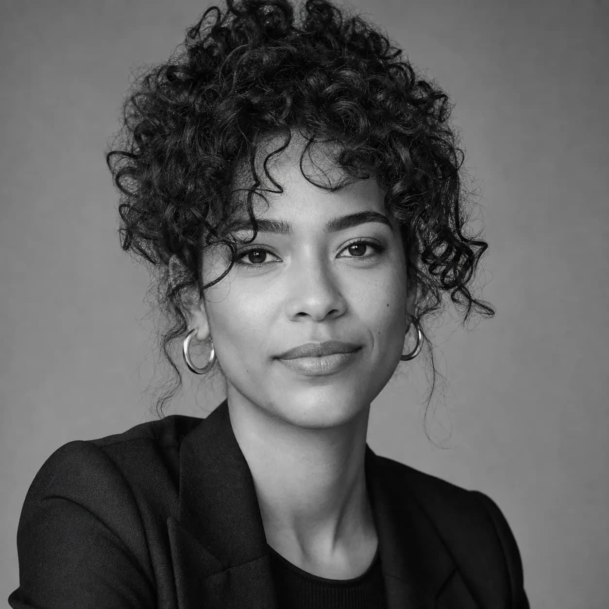 Black and white studio portrait of a presenter with curly hair