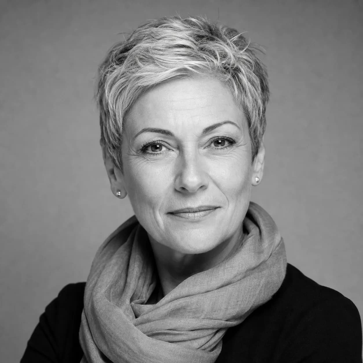 Black and white studio portrait of a presenter with cropped silver hair