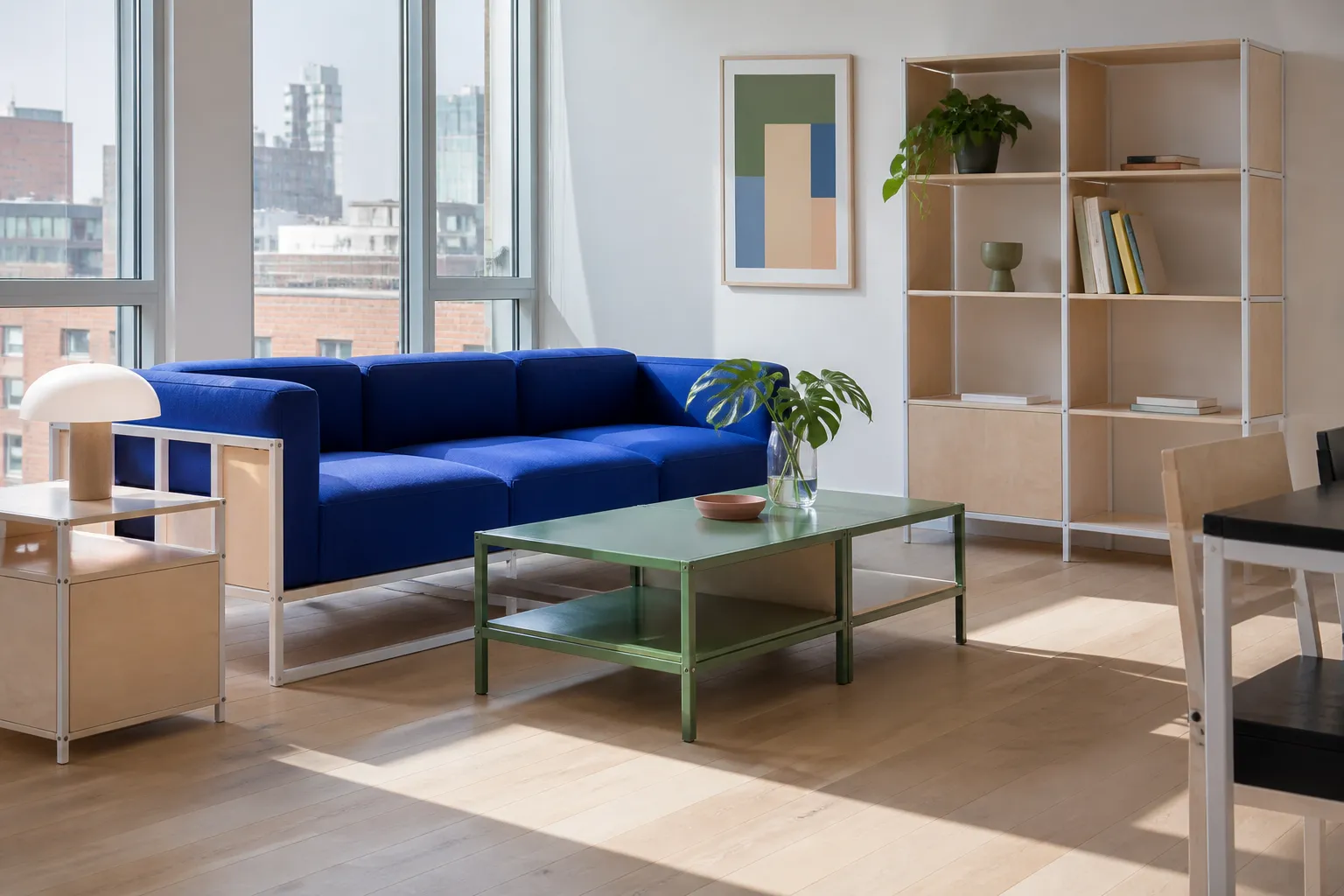 A bright apartment living room with a cobalt sofa, a deep green low table and a shelving unit in use