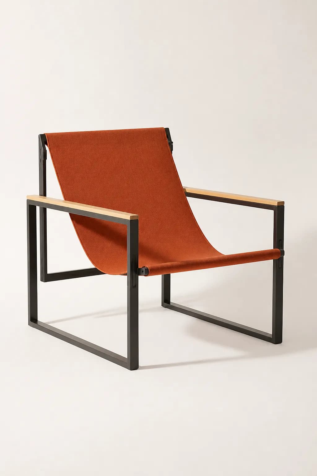 A lounge chair with a rust orange canvas sling on a charcoal steel frame